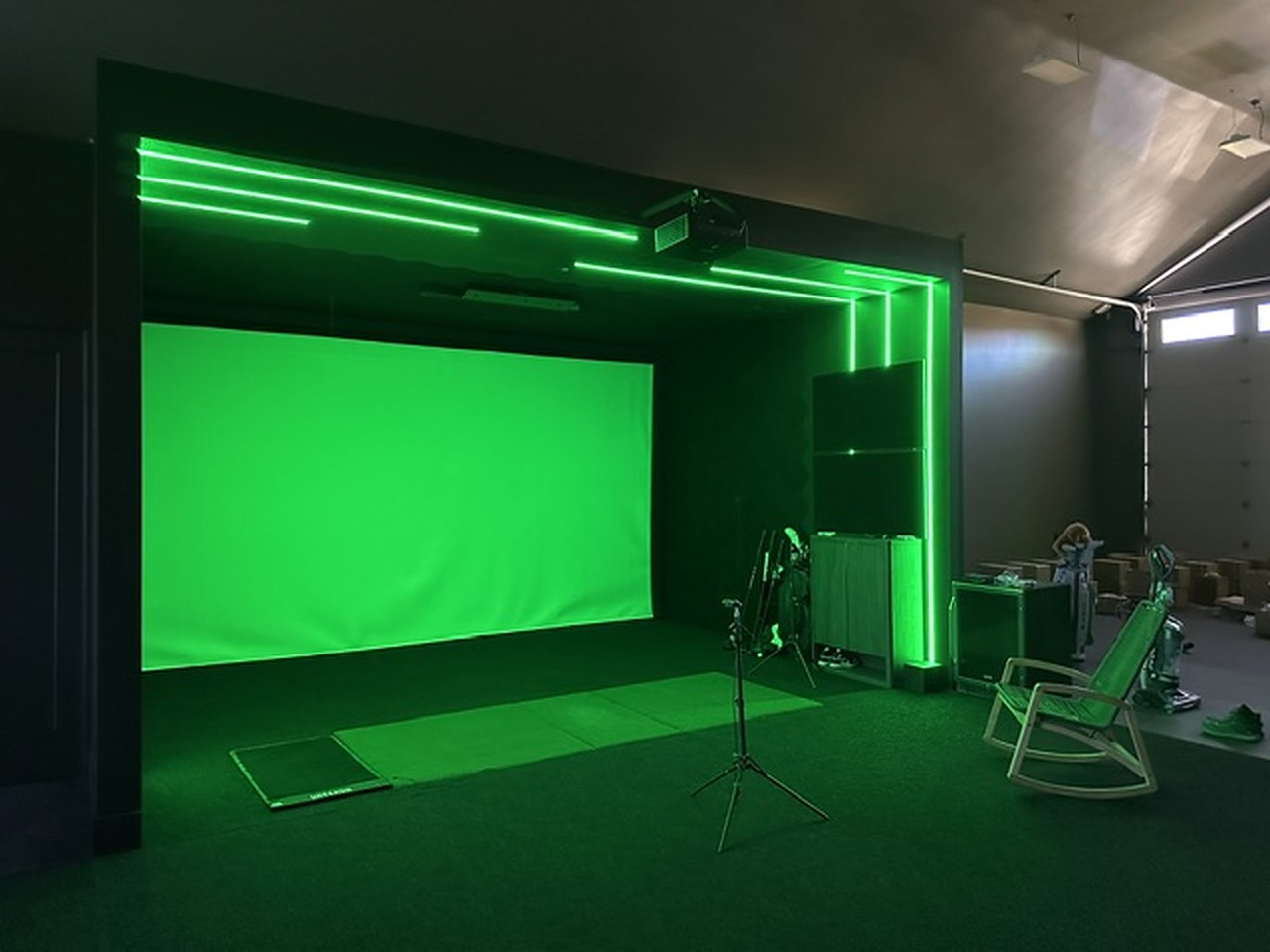 Golf simulator bay with custom green linear LED framing